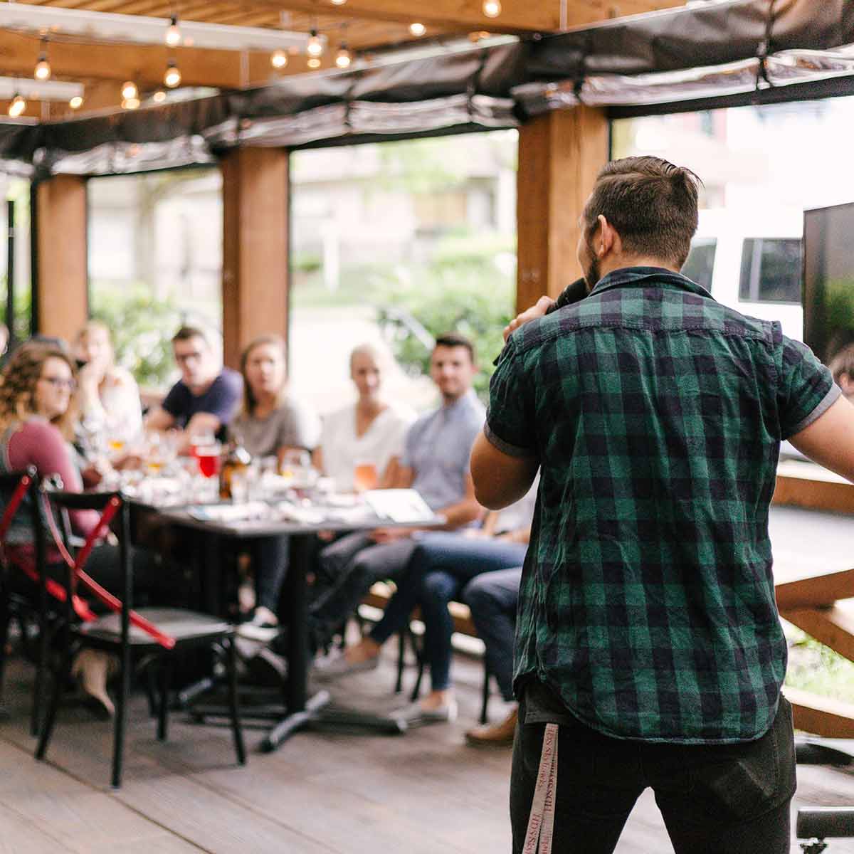 man speaking to a group of students in a casual restaurant setting